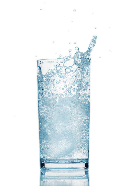 one glass of water with splash from falling ice cube, white background, isolated object stock photo