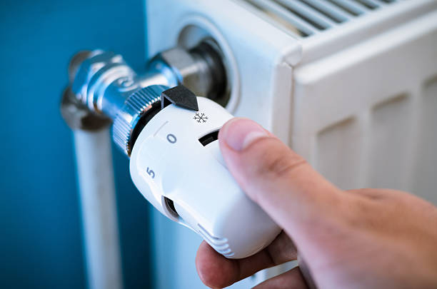 one hand adjust thermostat valve close up - warmte stockfoto's en -beelden