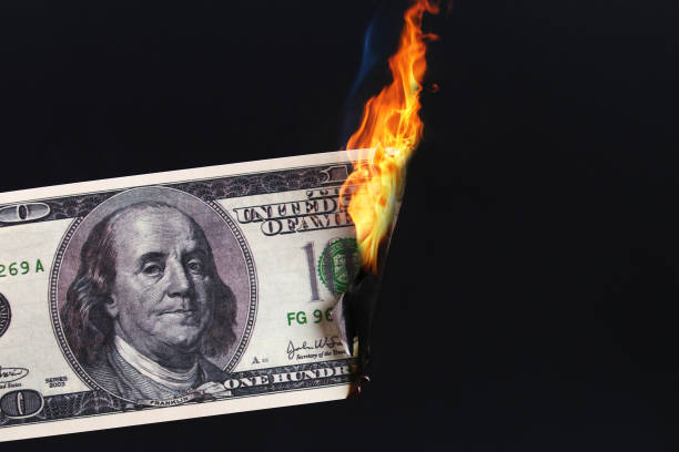 one hundred American dollar burning in fire flame. collapse of dollar. Devaluation. Falling currency stock photo