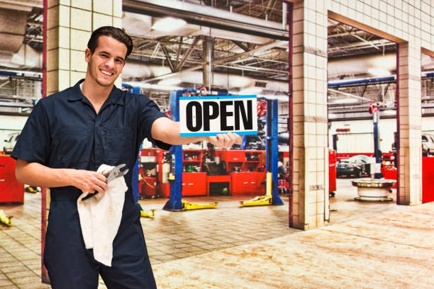one man only / one person / waist up / front view of 20-29 years old adult handsome people caucasian male / young men auto mechanic / mechanic / manual worker / repairman / technician / entrepreneur / owner repairing at the auto repair shop - garagem abrindo imagens e fotografias de stock