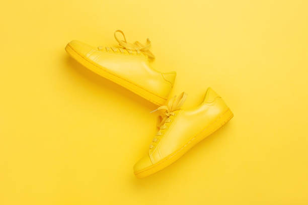 un paio di scarpe gialle su sfondo giallo. - shoes top view foto e immagini stock