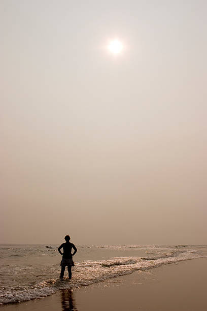 One person standing on the beach with sun stock photo