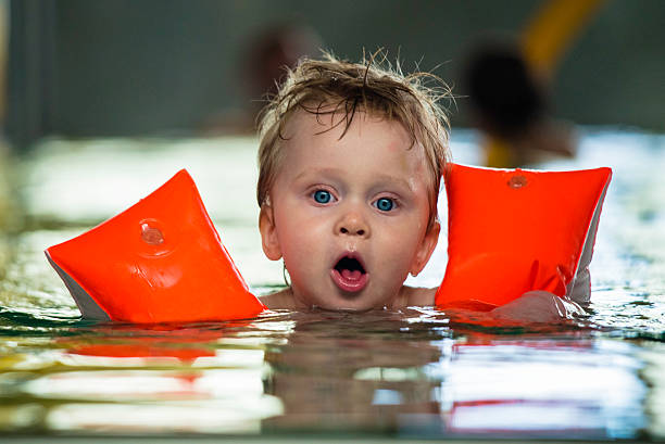 One year old child swims by himself with water wings stock photo
