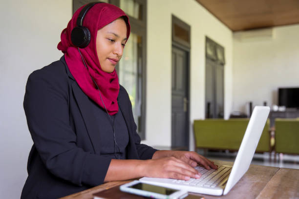 Online education in South East Asia during Covid 19 pandemic Portrait shot of Asian muslim teacher making online lessons on her laptop for students at home, during lockdown Covid 19 indonesian woman stock pictures, royalty-free photos & images