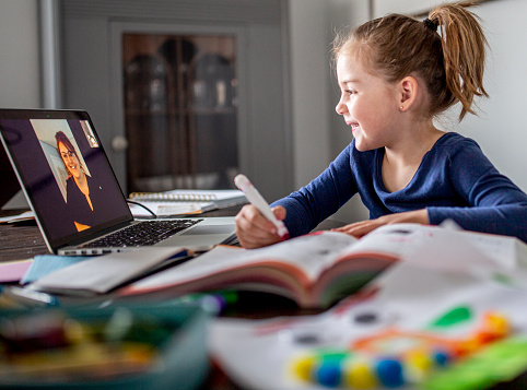 Little girl learns from home while her teacher teaches remotely.