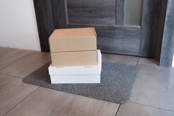 Online purchase delivery service concept. Courier delivery cardboard boxes at the door of the house. Parcel on the door mat near entrance door. Courier delivery cardboard boxes at the door of the house. Commercial entrance mats stock pictures, royalty-free photos & images