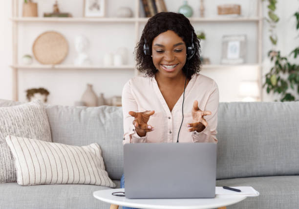 Online Tutoring Concept. Smiling black female tutor having video call with student Online Tutoring Concept. Smiling black female tutor having video call with student, giving language class by webcam, sitting on couch at home showing stock pictures, royalty-free photos & images
