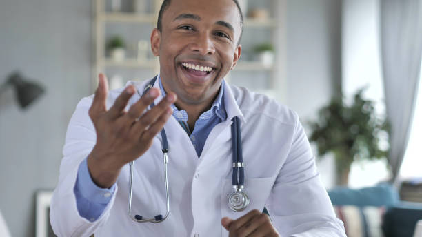 Online Video Chat with Patient by African-American Doctor, Camera View Online Video Chat with Patient by African-American Doctor, Camera View nurse talking to camera stock pictures, royalty-free photos & images