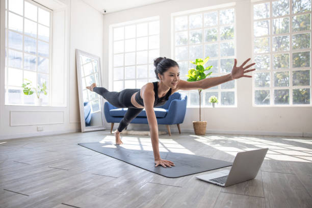 Online yoga instructor, Young Asian woman doing yoga stretching yoga at home. stock photo