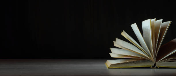 Open book, hardback book on wooden table on dark background. Back to school,education,reading. Copy space stock photo