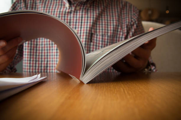 Open book in front of a checkered shirt on a wooden table stock photo
