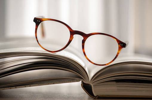 Open books and glasses over bokeh background