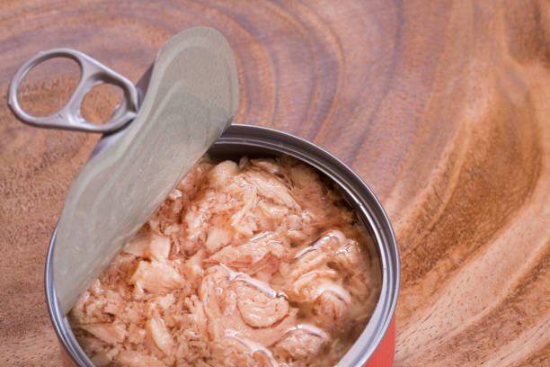 Open can of tuna on the wooden background. Top view stock photo