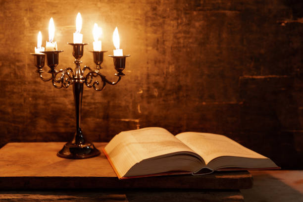 Open Holy Bible and candle on a old oak wooden table. stock photo