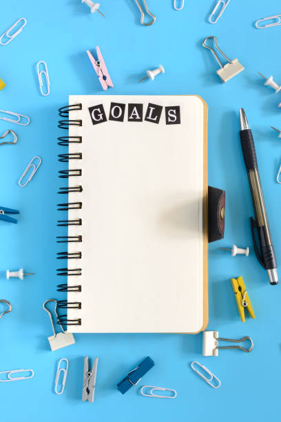 Open notebook on a light blue background with the word Goal. Stationery is in disarray. Beautiful background with place for text. Mock up. stock photo