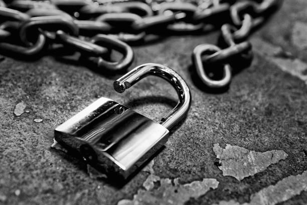 Open padlock and chain on a rough concrete surface, symoblizing freedom stock photo