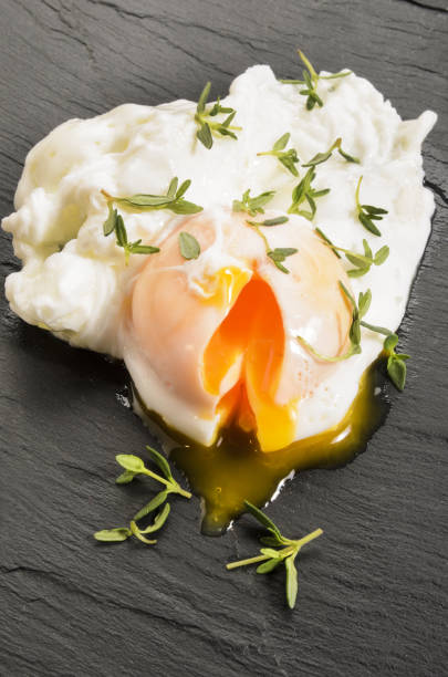 open poached egg with thyme on slate open organic poached egg with thyme on slate poached food stock pictures, royalty-free photos & images