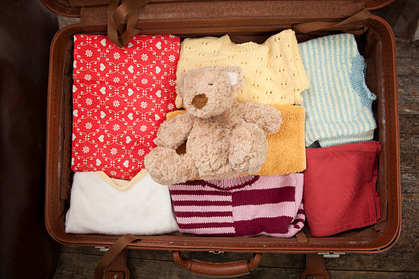 Open suitcase with clothes and teddy bear stock photo