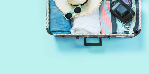 open koffer met vrouwelijke kleding voor reis op pastel blauw. bovenaanzicht met kopie ruimte. zomer concept reizen. - packing suitcase stockfoto's en -beelden