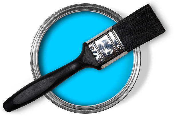 Open tin of blue paint, brush on top on white stock photo