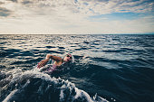 Female open water swimmer swimming forward crawl in sea.
