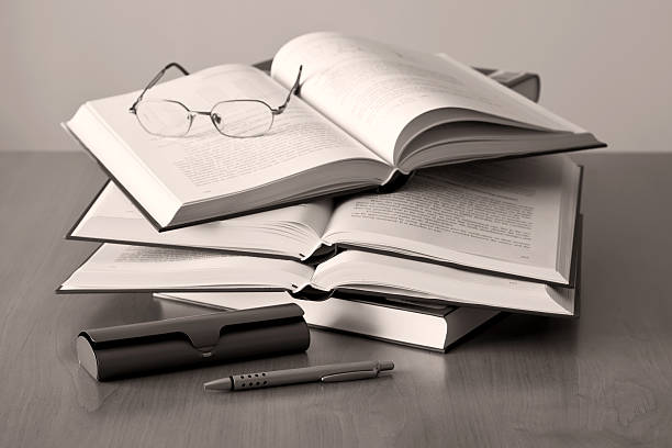 opened books pen and glasses on sepia background stock photo