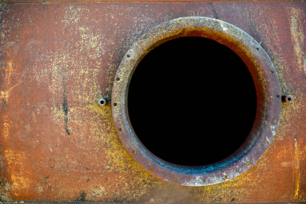 opened rusty manhole on orange fuel tank stock photo