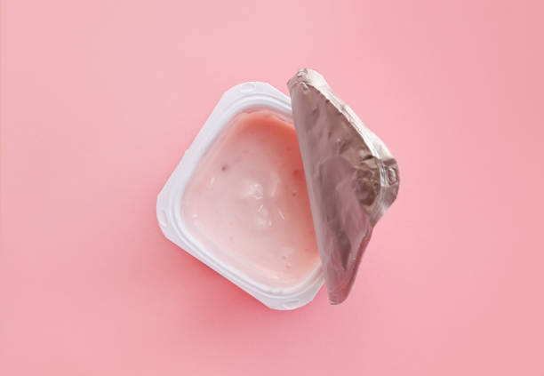 Opened strawberry yogurt or pudding  in white plastic cup, flat stock photo