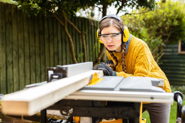 Operating electric sawing machine. Young independent home business owner doing environmental woodworking using recycled materials for furniture. stock photo