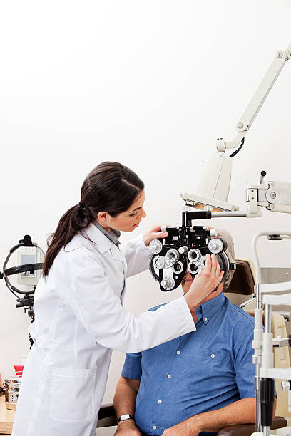 Optometrist administering eye checkup with phoropter stock photo