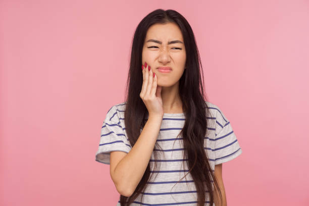 munhälsa. porträtt av flicka med brunett hår i randig t-shirt röra hakan, känsla tandvärk - toothache woman bildbanksfoton och bilder