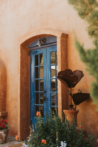 Italian accents on a sonoran southwestern style home. Blue italian or french doors with metal florals by the doorway.