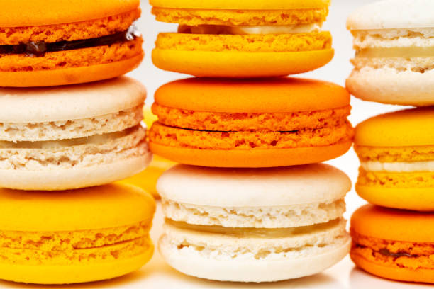 Orange and yellow macarons or macaroons stacked or piled. Closeup. stock photo