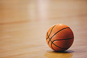 istock Orange basketball ball on wooden parquet. Close-up image of basketball ball over floor in the gym 1292401641