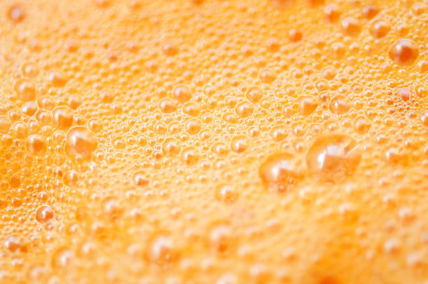 Orange Carrot Smoothie Bubbles Orange and carrot juice smoothie bubble froth full frame background orange smoothie stock pictures, royalty-free photos & images