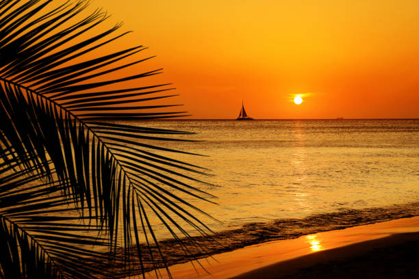 orange colored shiny seascape with sailboat over sunset sky stock photo
