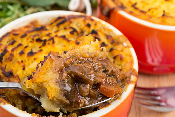 Orange dish of cottage pie being served with a large spoon stock photo