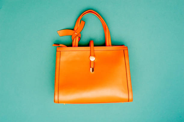 borsa arancione su sfondo verde smeraldo - borsetta foto e immagini stock