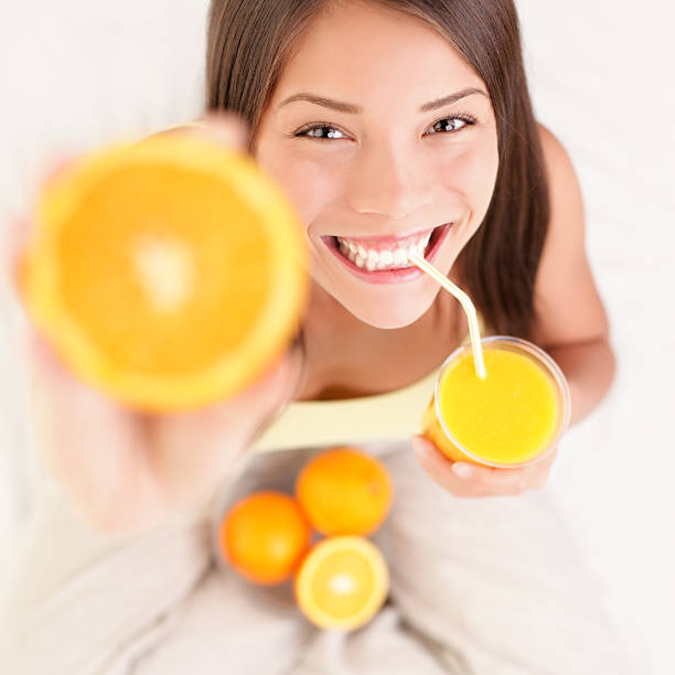 Orange juice drinking woman stock photo