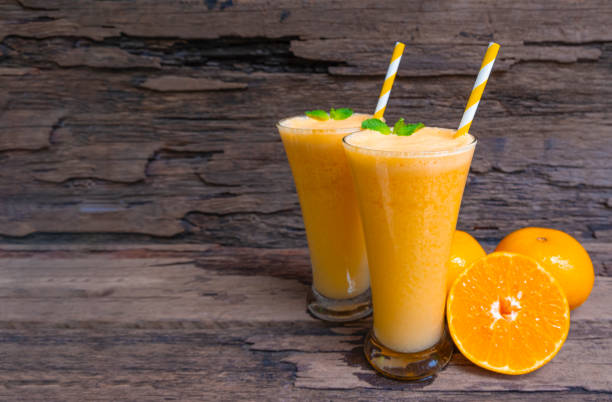 Orange juice fruit smoothies yogurt drink yellow healthy delicious taste in a glass slush for weight loss on wooden background. Orange juice fruit smoothies yogurt drink yellow healthy delicious taste in a glass slush for weight loss on wooden background. orange smoothie stock pictures, royalty-free photos & images