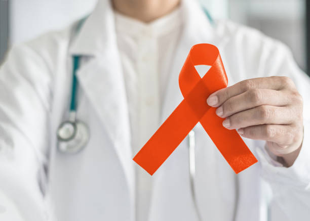 orange ribbon for raising awareness on leukemia, kidney cancer, rds multiple sclerosis, adhd illness in doctor's hand (bow isolated with clipping path) - world cancer day imagens e fotografias de stock