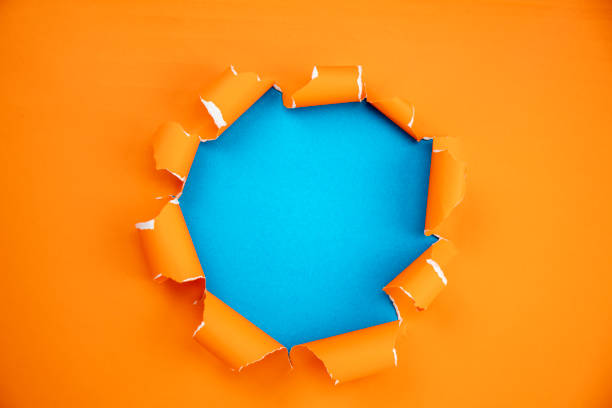 Orange ripped open paper on blue paper background,space for your message on torn paper stock photo