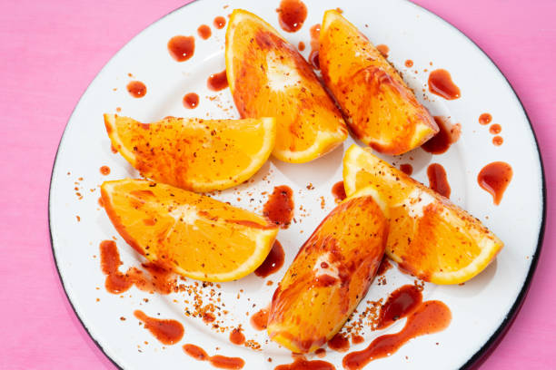 rodajas de naranja con chile en polvo y chamoy sobre fondo colorido - fruta con chamoy fotografías e imágenes de stock