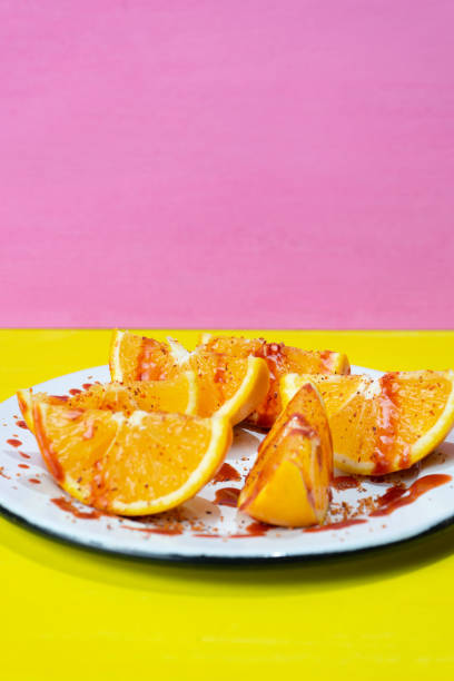 rodajas de naranja con chile en polvo y chamoy sobre fondo colorido - fruta con chamoy fotografías e imágenes de stock