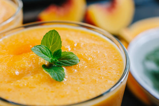 Orange smoothie with leaves of fresh mint Close-up shot of orange smoothie with leaves of fresh mint papaya smoothie stock pictures, royalty-free photos & images