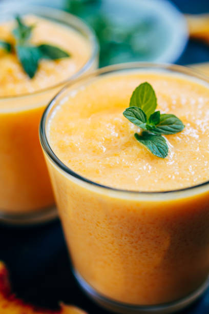 Orange smoothie with leaves of fresh mint From above view of two glass orange smoothie with leaves of fresh mint papaya smoothie stock pictures, royalty-free photos & images