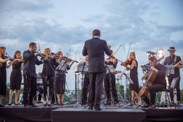 Orchestra playing classic instrumental music under cloudy sky stock photo