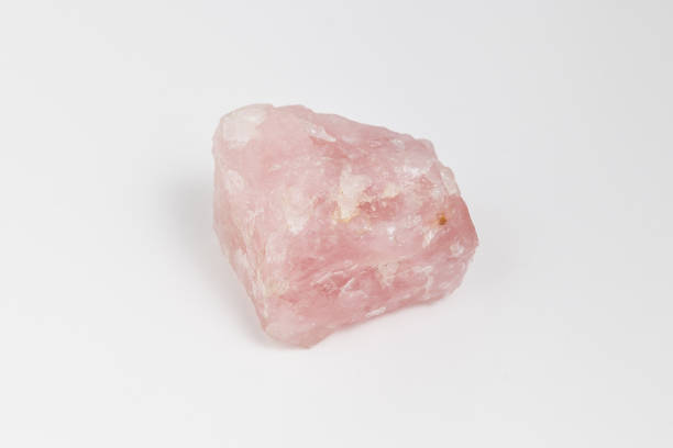 Ore rose quartz on white background. Ore rose quartz on white background.  is a type of quartz which exhibits a pale pink to rose red hue. The color is usually considered as due to trace amounts of titanium, iron, or manganese, in the massive material. rose quartz stock pictures, royalty-free photos & images