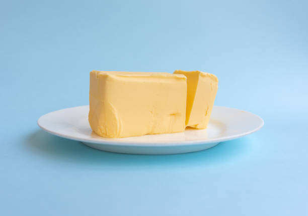 biologische boter op wit bord tegen blauwe achtergrond - boter stockfoto's en -beelden