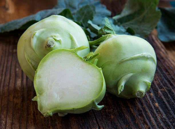 Organic fresh kohlrabi root vegetable wholes and a half on a wooden table stock photo